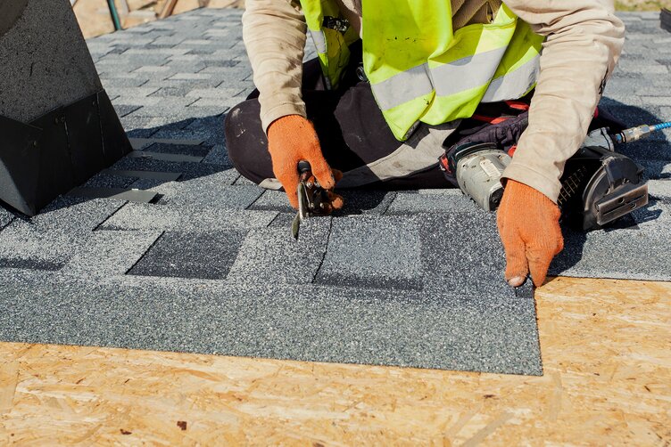 A man puts asphalt shingles on a roof